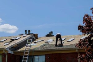 Homeowner examining roof gutters from the ground beside a snow-ready house