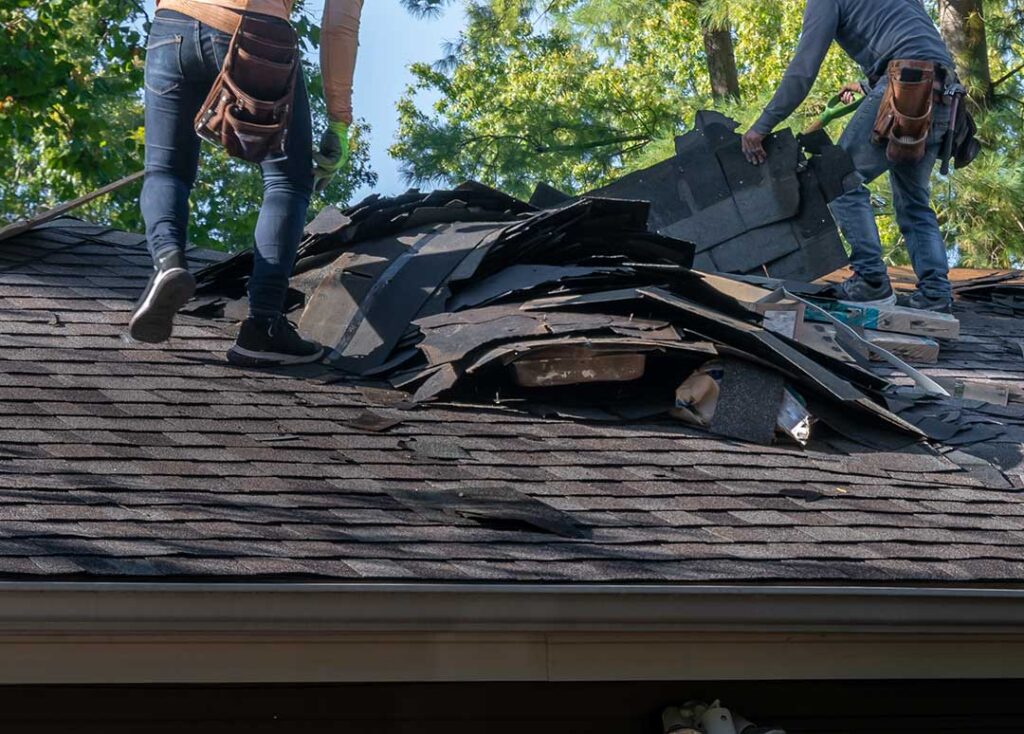 Rainwater flowing through clean gutters and downspouts along a residential roof during a spring storm.